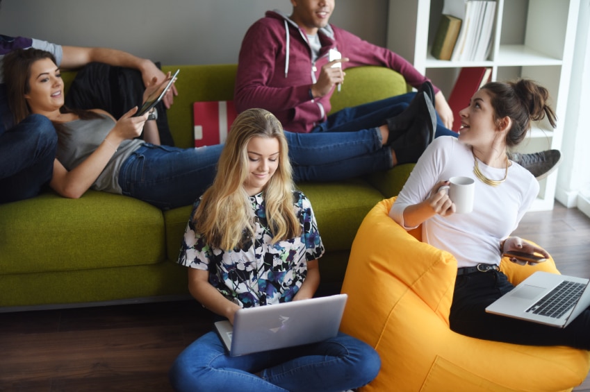 Les adolescents se détendent sur un canapé et un pouf avec un ordinateur portable